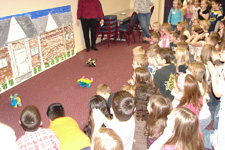 Photo of elementary school children cheering on battery-operated pigs racing on the carpet